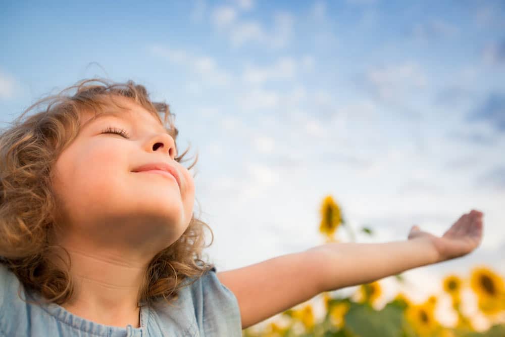 Groupe d'enfants et animatrice pratiquant la méditation en plein air sur l'herbe