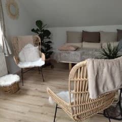 Espace de consultation apaisant avec fauteuils en rotin, coussins moelleux et plantes vertes